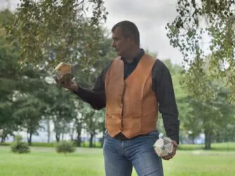 This photo shows the leather waistcoat on the front side. Customer, wearing the vest, stands casually under a birch tree.