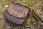 Round shaped leather handbag in mahogany, decorated with hand carved Estonian folk pattern.