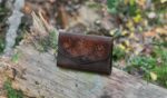 Leather purse decorated by hand carved flower image.