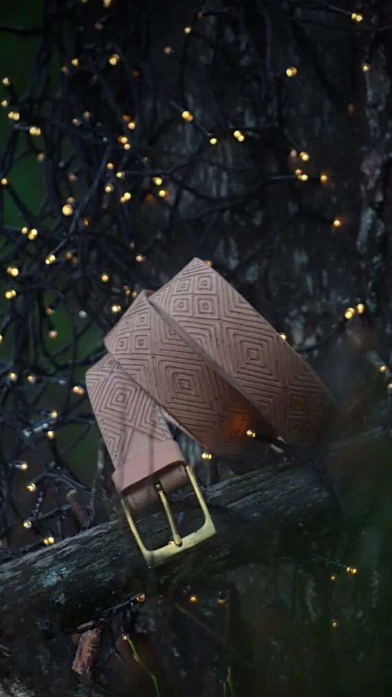 Light leather belt in dark forest setting. There are some small sparkling lights on the background.