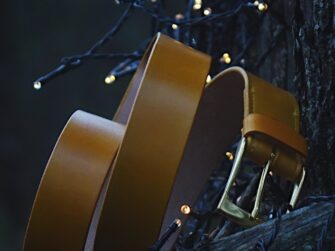 Photo is taken in the darkening forest where the belt is set onto the fallen tree. The whole scene surrounding the yellow belt is a bit blue toned. Some small sparkling lights in the background and foreground give it a nice warmer feeling.