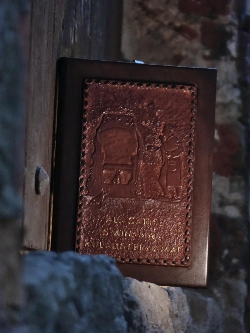 Book is placed onto stone door frame. There is a massive wooden door behind it.