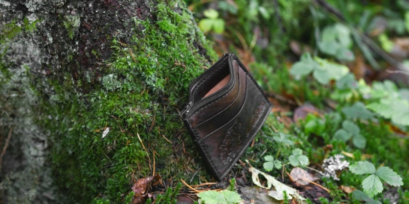 Leather card case placed onto the mossy forest ground.