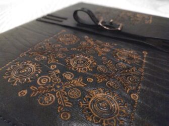 This photo shows a close up of the carved image on the covers. It also shows an interesting designed fastening.