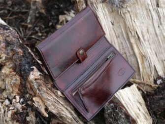 Large wallet opened on the ground, beside light old fallen tree.